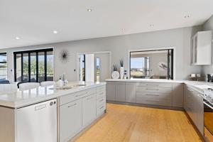 a kitchen with white cabinets and white counters at Luxury Lake Hood Holiday Home in Wakanui