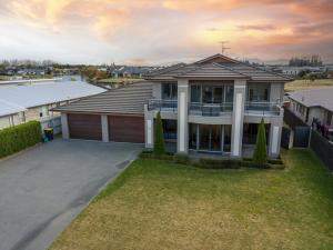 a large house with a garage in a yard at Waterfront Lake Hood Luxury in Wakanui