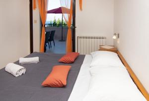 łóżko z pomarańczowymi i białymi poduszkami w obiekcie Apartments Grzin w mieście Mošćenička Draga