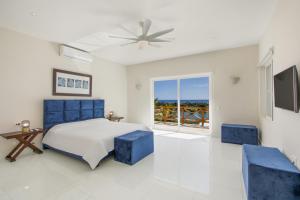a bedroom with a bed and two blue chairs at Villa Okyanus with Fantastic Ocean View Chef Butler Maid Golf Cart in Punta Cana