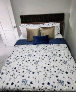 a bed with a blue and white comforter and pillows at Marhabi's home in Sonsonate