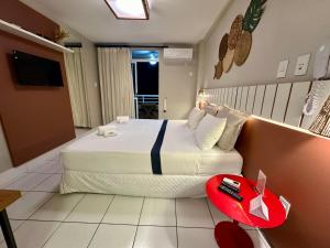 巴雷里尼亞斯的住宿－Gran Lençóis Flat Barreirinhas APT 510，一间卧室设有一张大床和一张红色的桌子。