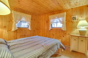 a bedroom with a bed and two windows at Cozy Thompson Lake Cabin with Boat Dock and Launch 