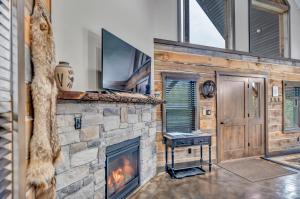a living room with a stone fireplace and a tv at Rustic Hideaway sleeps 4 Hot tub in De Soto
