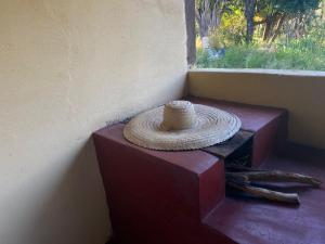 um chapéu de palha sentado numa mesa ao lado de uma janela em Espaço Amainar em Sobradinho