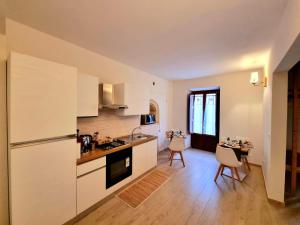 a kitchen with white cabinets and a table with chairs at Dimora Grotta Masciarelli in LʼAquila