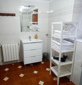 ein Badezimmer mit einem weißen Waschbecken und einem weißen Regal mit Handtüchern in der Unterkunft Casa Choureiro Apartamentos Rurales in Navia