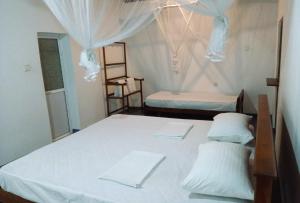 two beds in a room with white sheets at AB Nest Hiriketiya in Dickwella