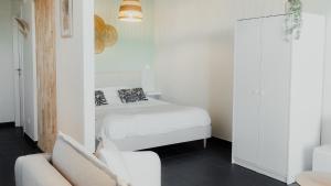 a white bedroom with a bed and a couch at Studio Saint-Martin in Tournai