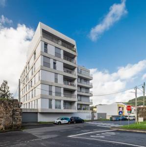 a tall white building with cars parked in front of it at Quiet & Comfy Azorean Sapphire in Fajã de Baixo