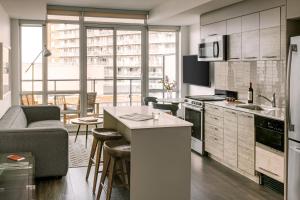 een keuken en een woonkamer met een bank en een tafel bij Sonder at The Liberty in Toronto