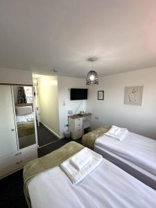 a hotel room with two beds and a television at Newmarket Road Studios and Suites By Tas Accommodations in Cambridge