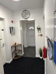 a hallway with a clock on the wall and a door at Newmarket Road Studios and Suites By Tas Accommodations in Cambridge