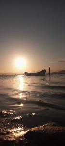 ein Boot am Strand bei Sonnenuntergang in der Unterkunft Chalés com vista para Lagoa de Ibiraquera in Imbituba