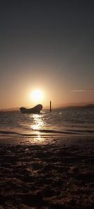 einen Sonnenuntergang am Strand mit einem Boot im Wasser in der Unterkunft Chalés com vista para Lagoa de Ibiraquera in Imbituba