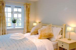 a bedroom with a bed with pillows and a window at Luxury barn with tennis court in South Downs National Park in Chichester