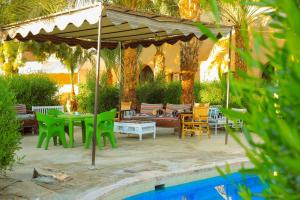 a patio with a table and chairs under an umbrella at Sekhmet Retreat Centre in Luxor