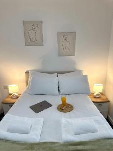 a bed with a tray and a drink on it at Newmarket Road Studios and Suites By Tas Accommodations in Cambridge
