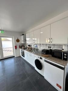 uma grande cozinha com armários brancos e um lavatório em Newmarket Road Studios and Suites By Tas Accommodations em Cambridge