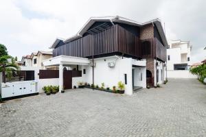 a white house with a black roof and a driveway at LA FIFTHIN VILLA in Lekki