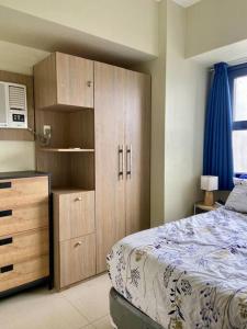 1 dormitorio con 1 cama y armario de madera en Horizon 101 - champito's place, en Cebú