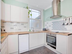 a white kitchen with white cabinets and a window at Lovely 2-Bed Apartment Colyton, nr. Jurassic Coast in Colyton