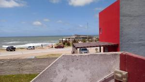 a red building next to a beach with the ocean at El Paso in Santa Clara del Mar