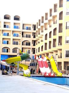 a pool with a slide in front of a hotel at Juliana beach resort in el ahead st in El Gouna +5 photos