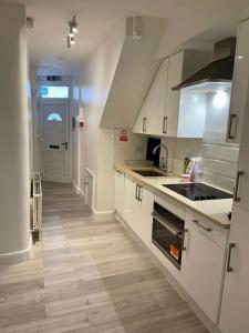 a kitchen with white cabinets and a wooden floor at Three bed Ensuites in Edgware in Edgware