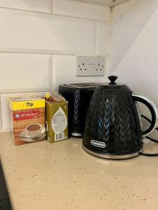 a black tea kettle and a box on a counter at Three bed Ensuites in Edgware in Edgware