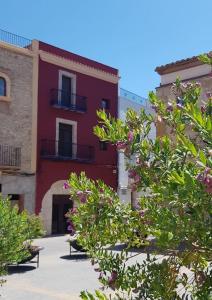 un bâtiment rouge avec des plantes devant dans l'établissement Casa de pueblo, entre mar y montaña, con spa. Plaza Mayor, à Sant Jordi
