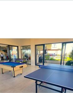 2 mesas de ping pong en una habitación con ventanas en Coastal Retreats, en Ballito