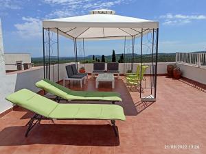 eine Terrasse mit grünen Stühlen und einem weißen Sonnenschirm in der Unterkunft Casa de pueblo, entre mar y montaña, con spa. Plaza Mayor in Sant Jordi