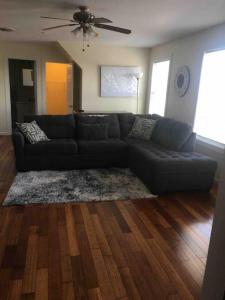 een woonkamer met een zwarte bank en houten vloeren bij Lovely one bedroom with free parking in Schenectady