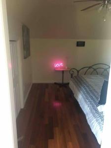une chambre avec un lit avec un signe néon qui dit amour dans l'établissement Lovely one bedroom with free parking, à Schenectady