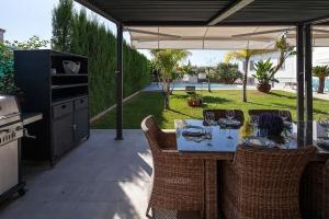 eine Terrasse mit einem Tisch und Stühlen unter einem Sonnenschirm in der Unterkunft Espectacular villa close to Sevilla - Sevillarooms in Valencina de la Concepción