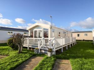 a mobile home with a porch and a deck at Snape Lodge in Abergele