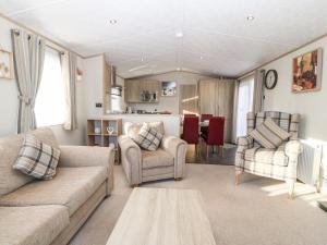 a living room with a couch and two chairs at Snape Lodge in Abergele