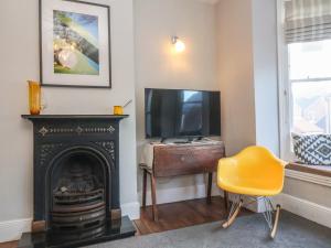 a living room with a fireplace and a television at Osprey in Southwold