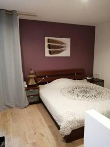 1 dormitorio con cama blanca y pared morada en Appartement ZEN ET COSY, en Estrablin