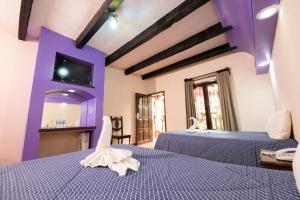 2 camas en una habitación con paredes moradas en Hotel D’Monica en San Cristóbal de Las Casas