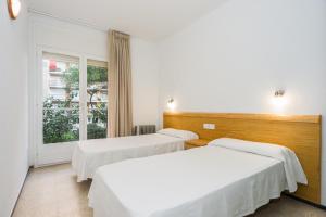 two beds in a room with a window at Apartamentos Blanes-Condal Costa Brava in Blanes
