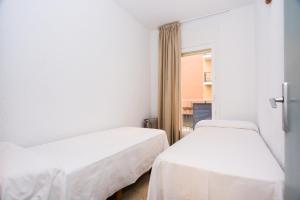 two beds in a room with a window at Apartamentos Blanes-Condal Costa Brava in Blanes