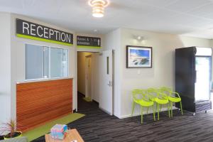 a waiting room with yellow chairs and a reception door at Palm Beach Hotel in Gold Coast