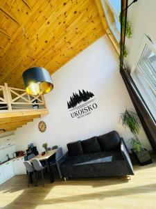 a living room with a black couch and a table at UKOISKO Bieszczady in Ropienka