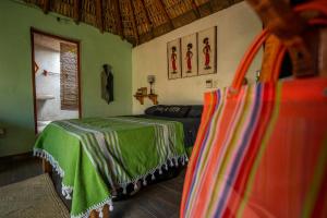 a bedroom with a bed with a green blanket at CASA AUM in Brisas de Zicatela