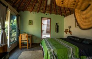 a bedroom with a bed and a table and a window at CASA AUM in Brisas de Zicatela