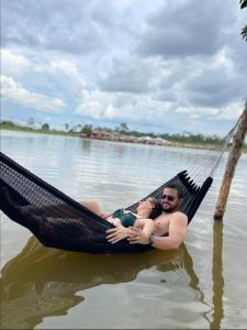 a man and woman laying in a hammock in the water at Espaço Leão Eventos in Rio Branco