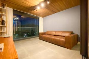 a brown leather couch in a room with a window at Atlântico Collection in Rio de Janeiro