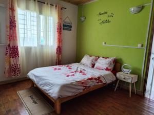 a bedroom with a bed with a green wall at Villa Fahasoavana in Antananarivo